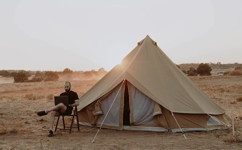 A person sitting in front of an open tent.